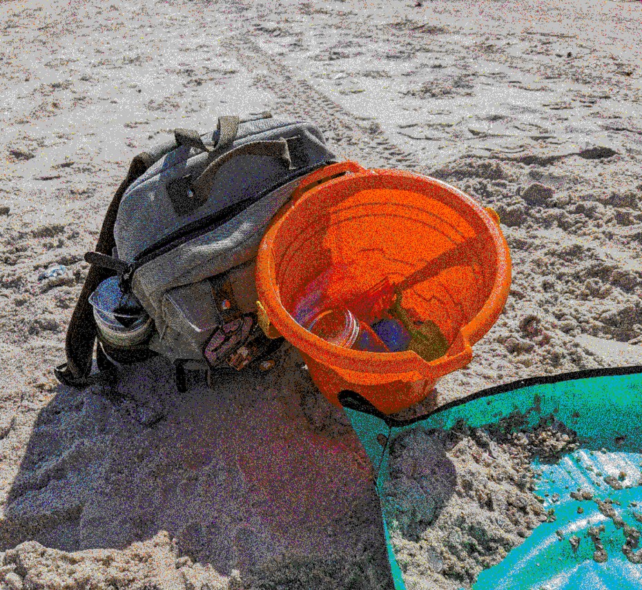 Backpack on beach with sifters and other beachcombing equipment